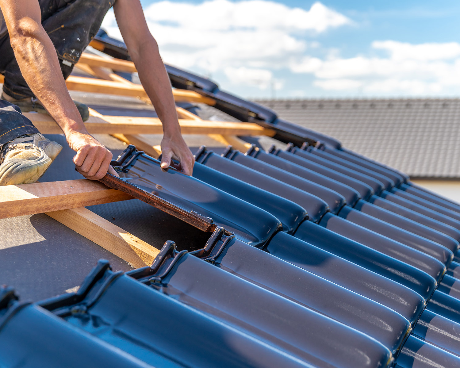 Un homme caucasien installant une tuile sur un toit en construction
